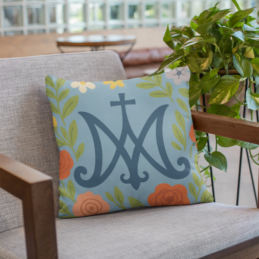 Decorative pillow with floral design and Marian Catholic symbol on a chair indoors.
